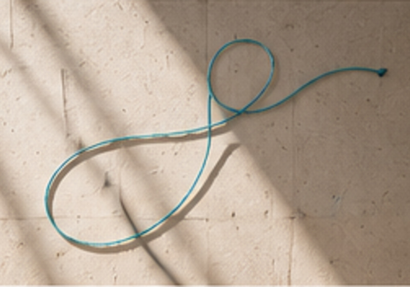A teal thread tracing a path on a sunlit wall